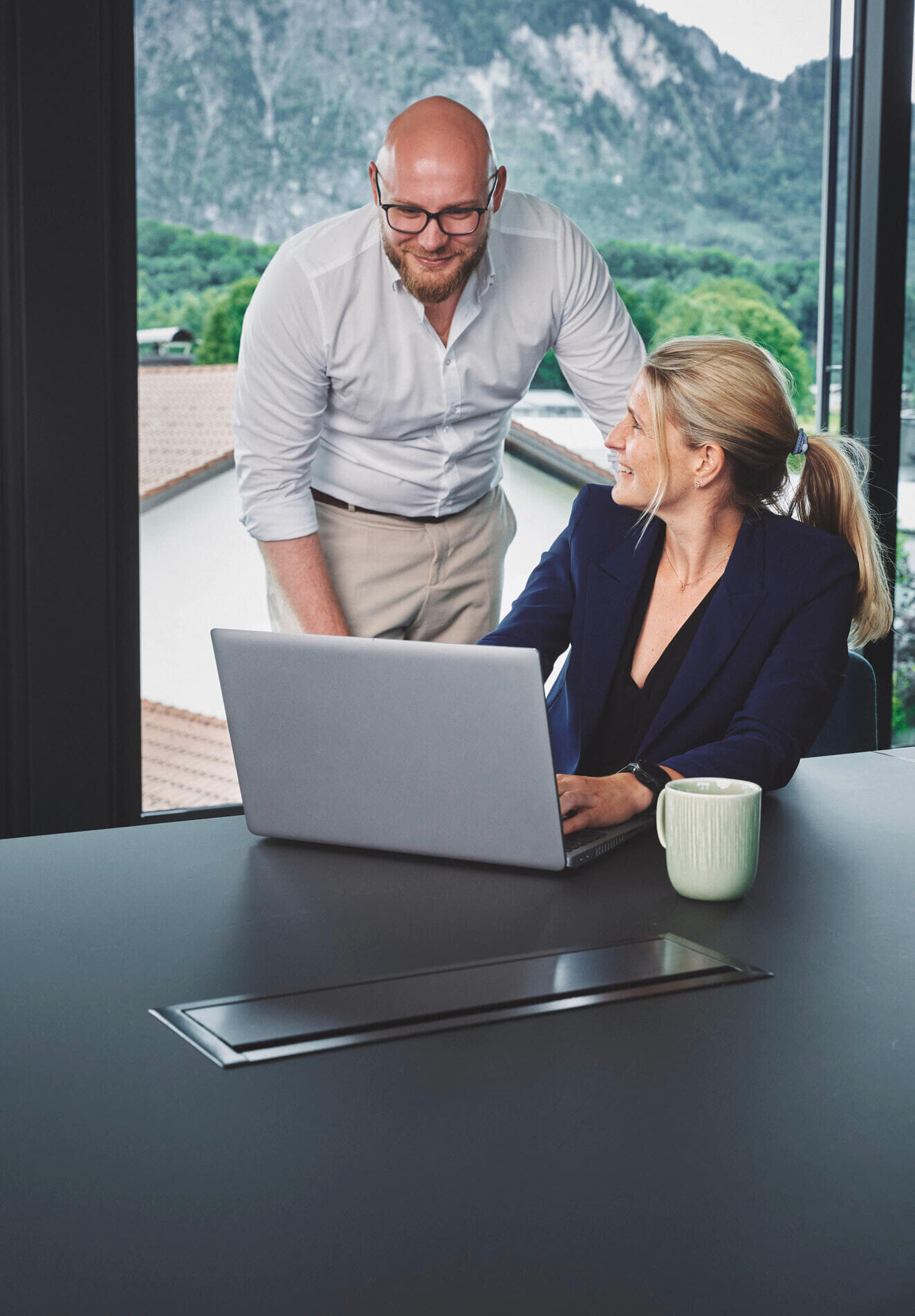 Mann und Frau schauen lächelnd auf einen Laptop